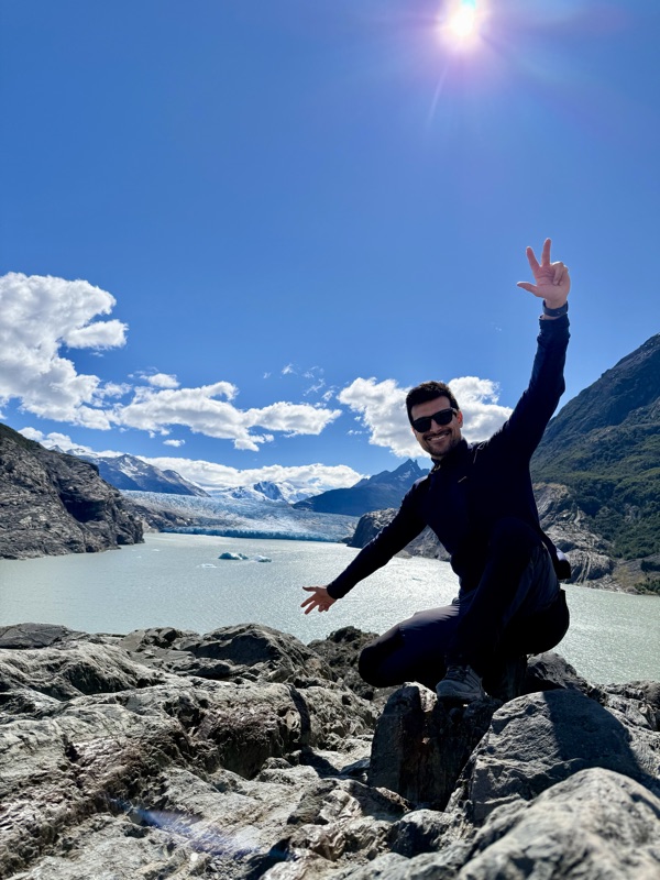 Waving from the rocks on the shore of Lago Grey, icebergs and the glacier behind