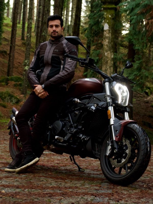 Sitting on a dark red motorcycle on a forest road